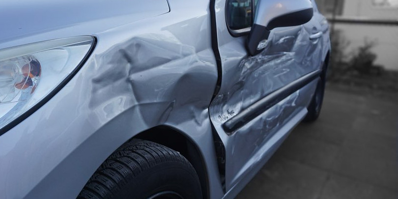 Ein Peugeot mit starken Schäden auf der linken Seite.